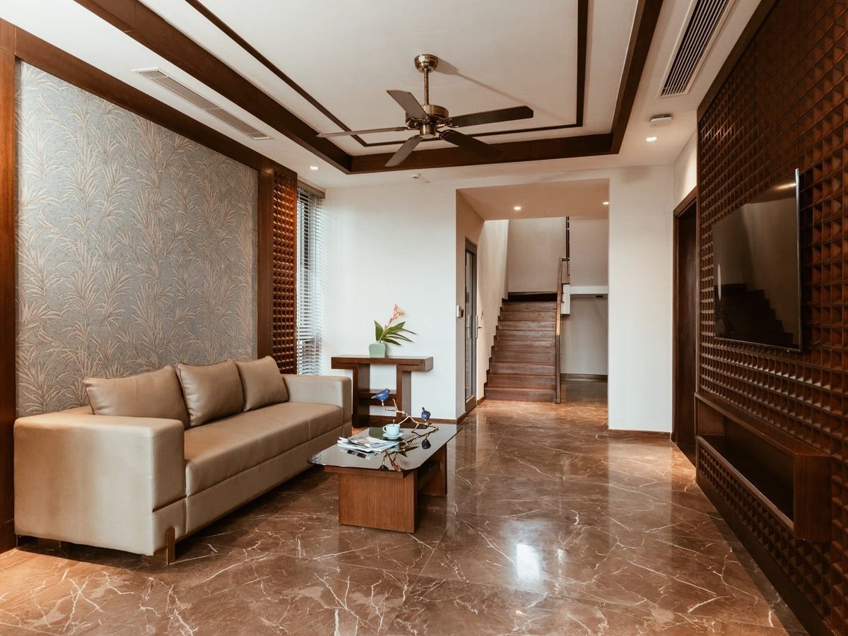 Phòng khách với sofa, sàn đá cẩm thạch, vách gỗ và cầu thang